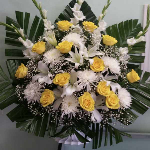 Yellow roses and white lilies arranged with palm leaves