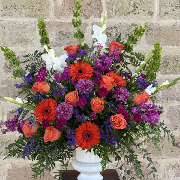 Bright mixed flower arrangement in a white vase with orange and purple blooms