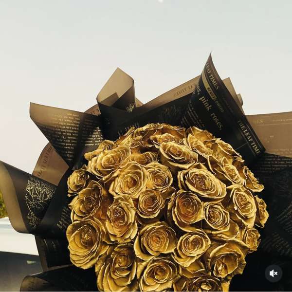 Bouquet of gold-colored roses wrapped in black and brown paper