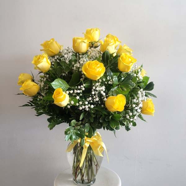 Yellow roses arranged in a clear glass vase with baby's breath
