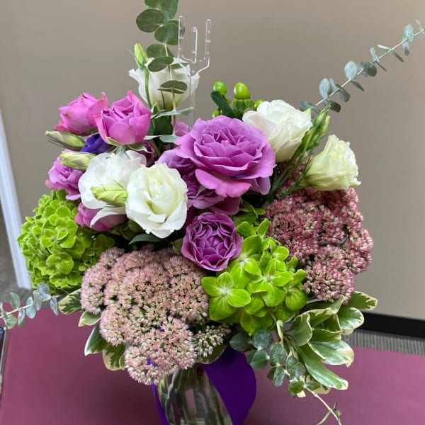 Bouquet of purple and white roses with green hydrangea in a vase