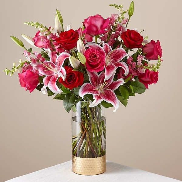 Bouquet of red and pink roses with pink lilies in a glass vase