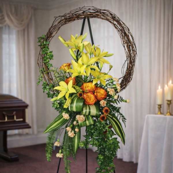 Standing floral spray with yellow lilies and orange roses on an easel