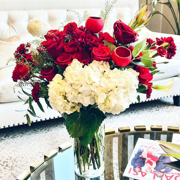 Red roses and white hydrangeas arranged in a clear glass vase