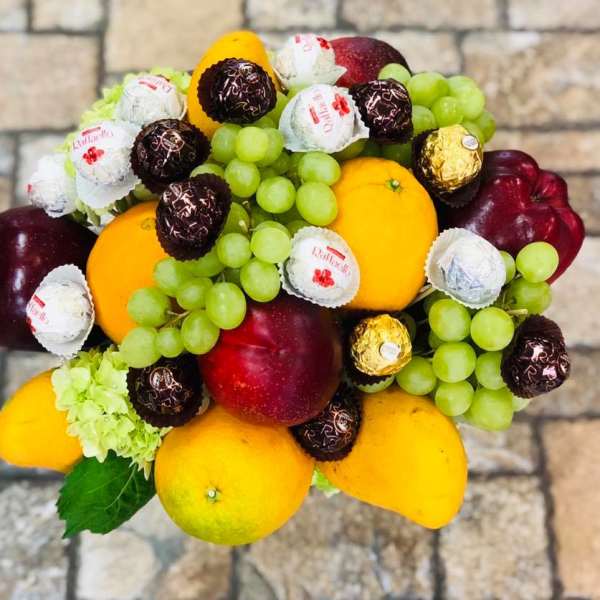 Fruit arrangement with grapes, mangoes, apples, and wrapped chocolates