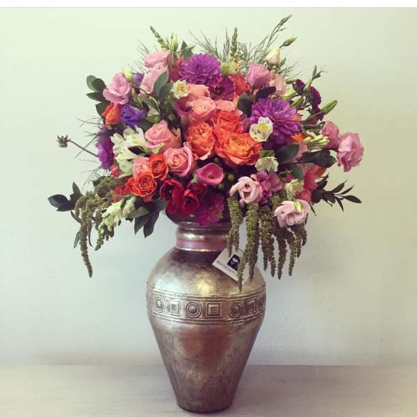 Mixed pink, purple, and orange flowers arranged in a metallic vase