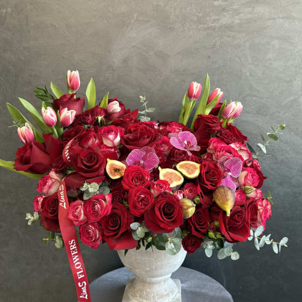 Red rose arrangement with pink tulips in a white pedestal vase