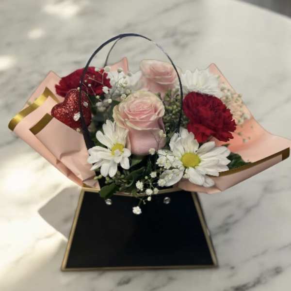 Bouquet of pink and red roses with white daisies in pink wrap