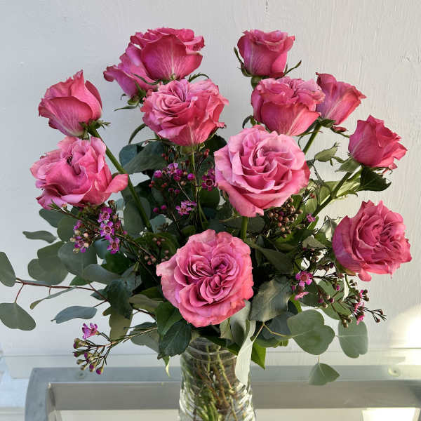 Pink roses arranged in a clear glass vase with greenery