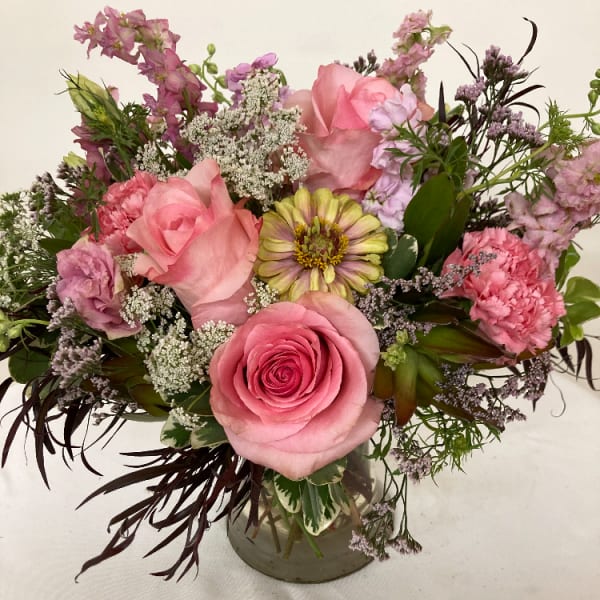 Pink rose bouquet in a glass vase with mixed blooms