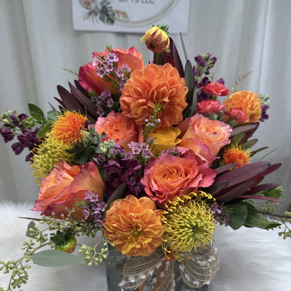 Bright mixed bouquet in a glass vase with orange, pink, and yellow blooms