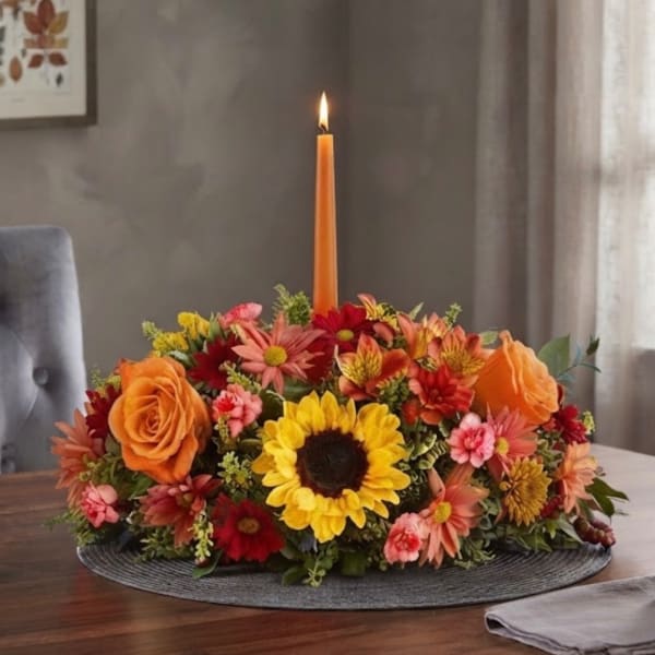 Autumn floral centerpiece with a lit orange taper candle