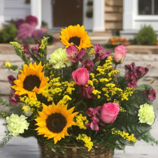 Basket arrangement with sunflowers, pink roses, and yellow filler flowers