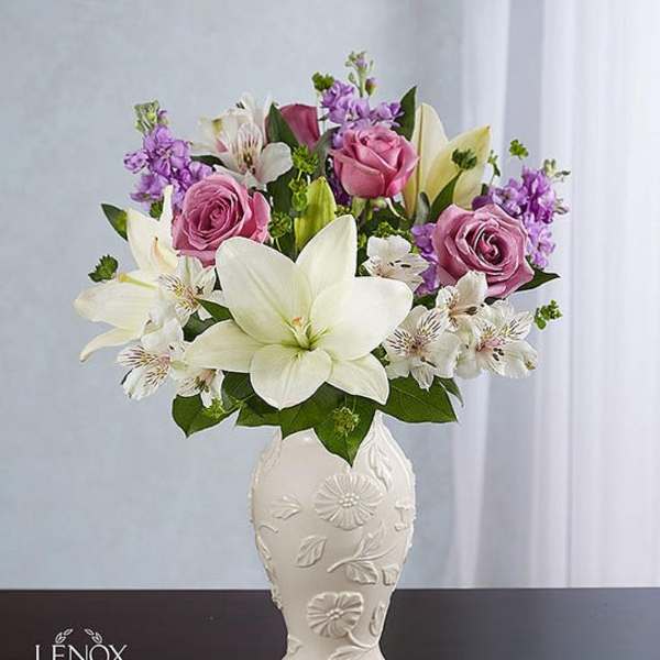 Pink roses and white lilies arranged in a decorative white vase