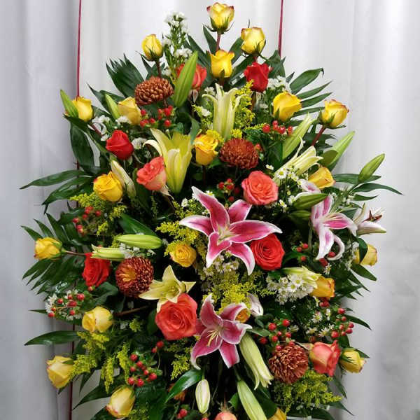 Standing floral spray with roses and lilies in yellow, pink, and red