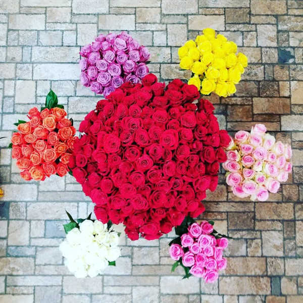 Six rose bouquets arranged in a heart shape on a stone floor