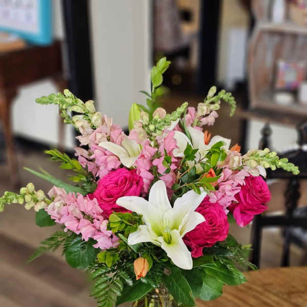 Bouquet of pink roses, white lilies, and pink snapdragons in a glass vase