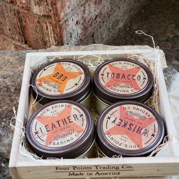 Four scented candles in a wooden crate with shredded filler