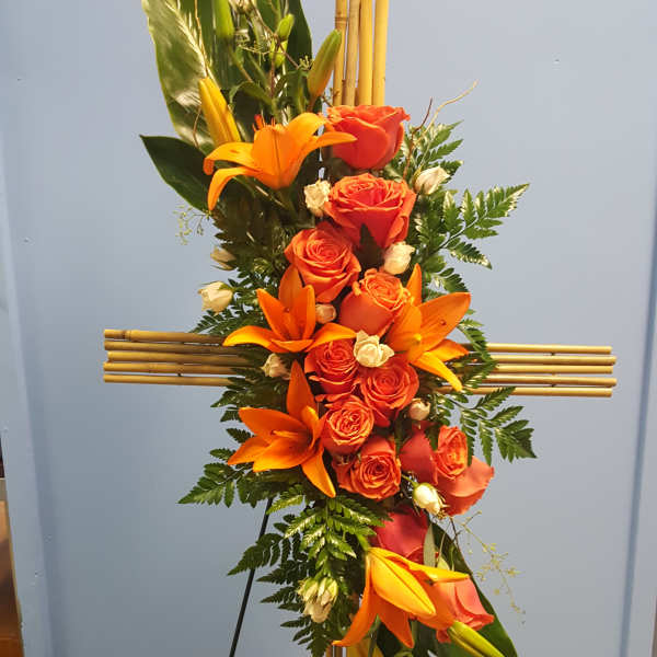 Tall floral standing spray with orange roses and lilies on a bamboo easel
