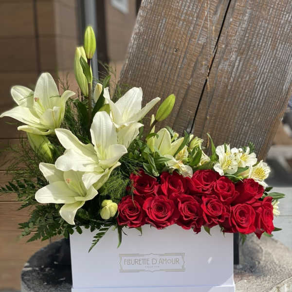 Red roses and white lilies arranged in a white box