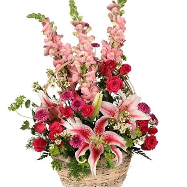 Basket arrangement with pink lilies, red roses, and tall pink snapdragons