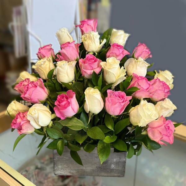 Pink and white roses arranged in a gray rectangular vase