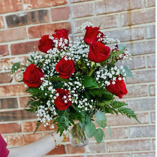 Bouquet of red roses and white baby's breath in a clear glass vase