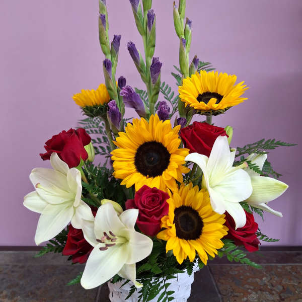 Basket arrangement with red roses, white lilies, and yellow sunflowers