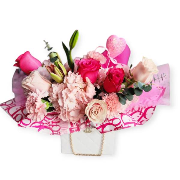 Pink rose and carnation bouquet with a heart topper in a gift bag