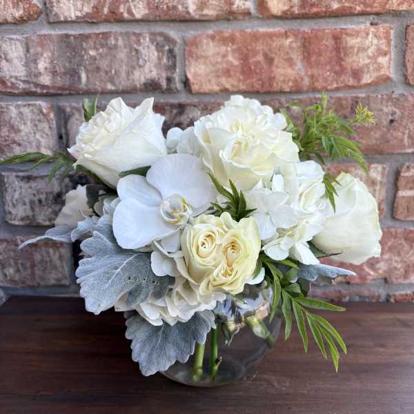 White roses and orchids arranged in a glass vase