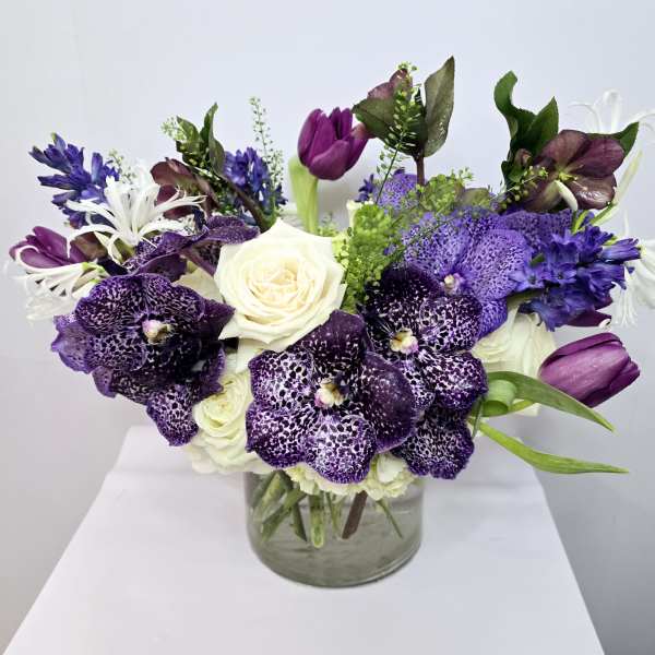 Purple and white floral arrangement in a clear glass vase