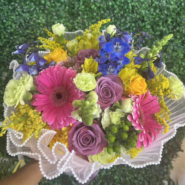 Colorful bouquet with pink gerberas, purple roses, and blue flowers