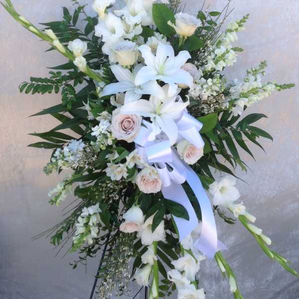 Tall white floral standing spray with lilies and roses on an easel