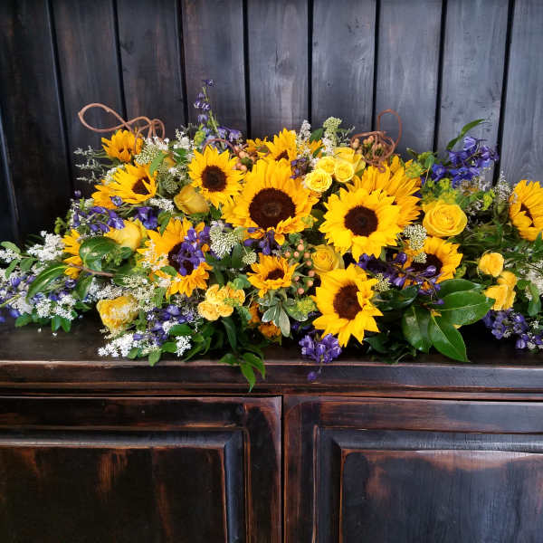 Large floral arrangement with sunflowers, yellow roses, and purple flowers