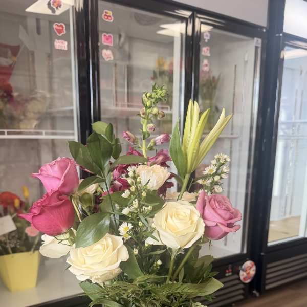 Mixed bouquet of pink and white roses with lilies and other flowers in a clear glass vase