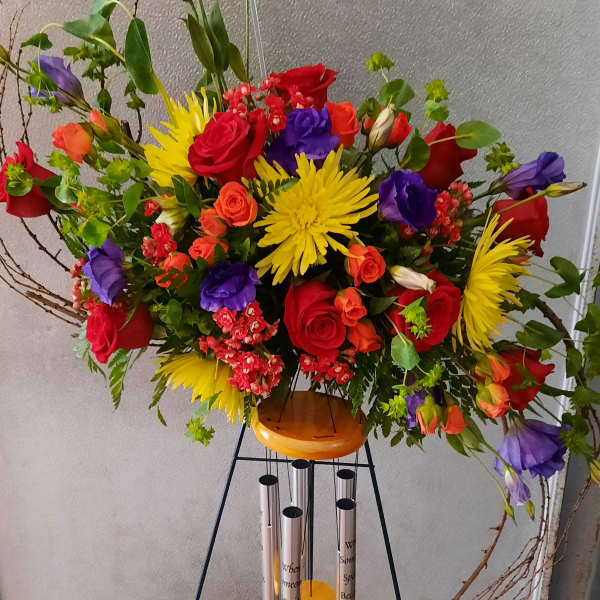 Tall mixed bouquet with red, yellow, purple, and orange flowers on a stand