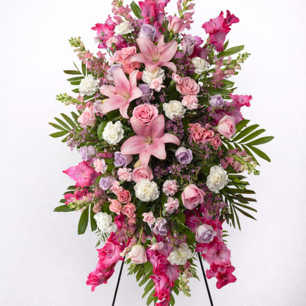 Large pink and lavender funeral spray on a black easel