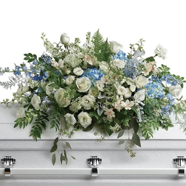White and blue floral casket spray with roses and hydrangeas