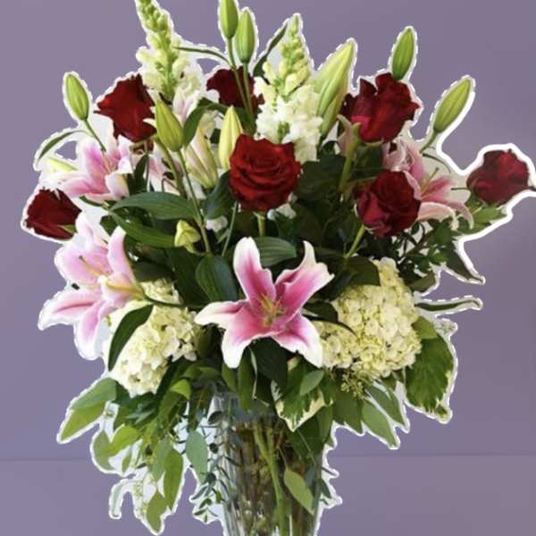 Bouquet of red roses and pink lilies in a clear glass vase