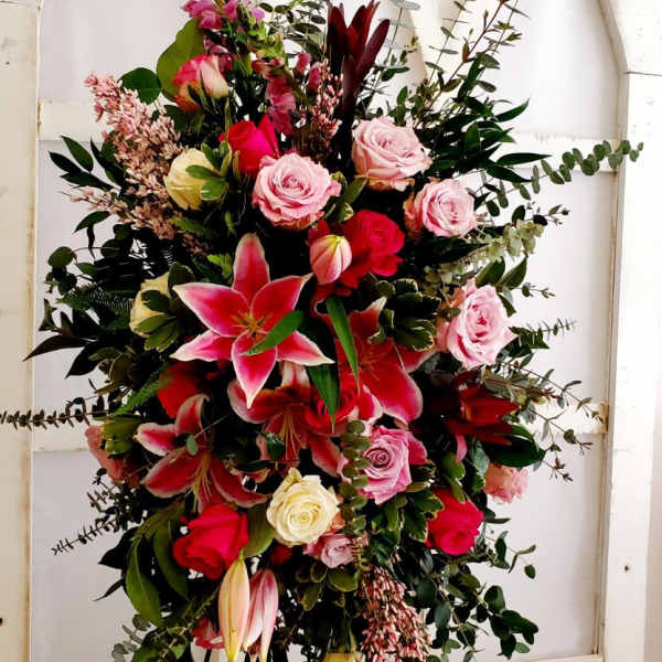 Tall floral spray with pink roses and lilies on a stand