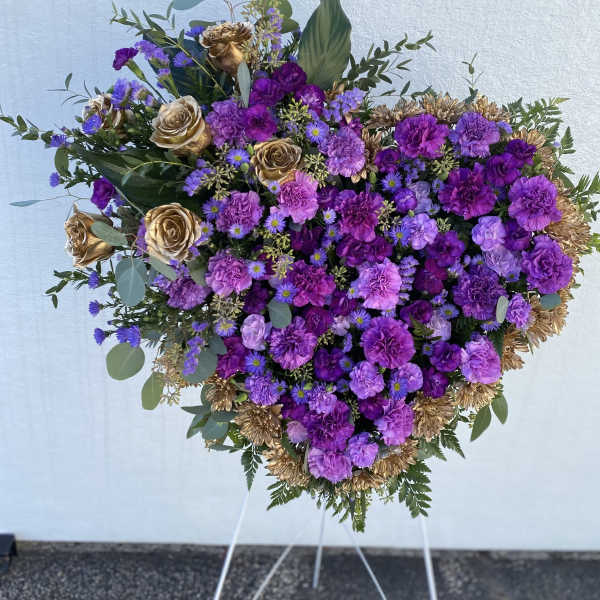 Heart-shaped purple floral spray with gold roses on a stand