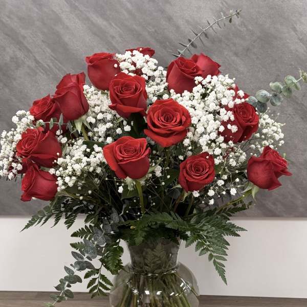 Red roses arranged in a clear glass vase with white baby's breath