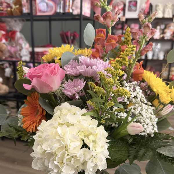 Mixed bouquet in a clear glass vase with pink, white, yellow, and orange flowers