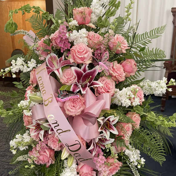 Large pink and white funeral spray with roses and lilies on a stand