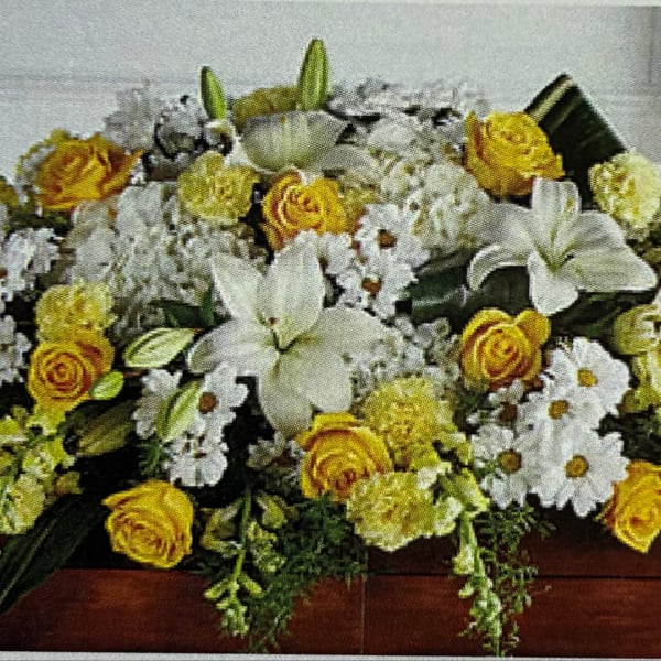 Yellow roses and white lilies arranged with white daisies in a low bouquet.