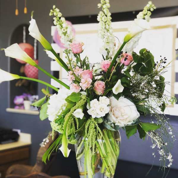 Tall floral arrangement with white calla lilies and pink roses in a glass vase
