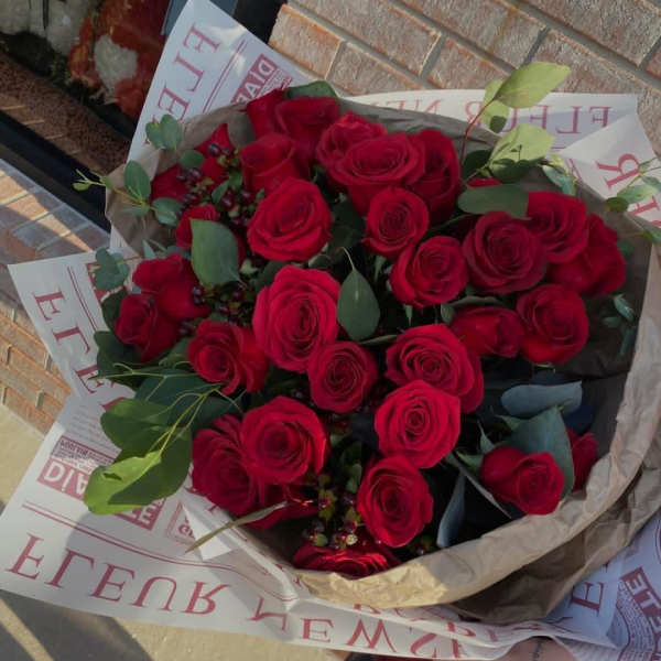 Bouquet of red roses wrapped in paper with greenery