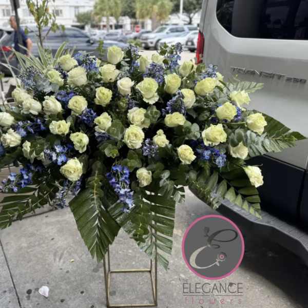 Large floral spray of white roses and blue flowers on a stand