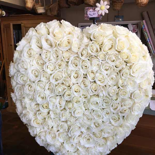 Heart-shaped arrangement of white roses on an easel