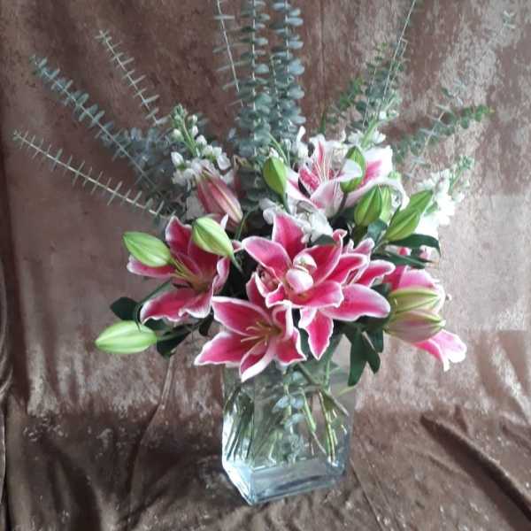 Pink lilies and eucalyptus in a clear glass vase